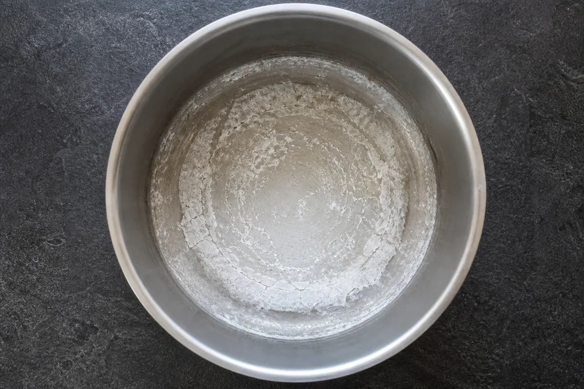 Fond d’une casserole en inox couvert d’un dépôt blanc de tartre séché, vue de dessus